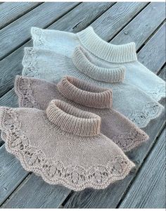 three knitted sweaters sitting on top of a wooden floor