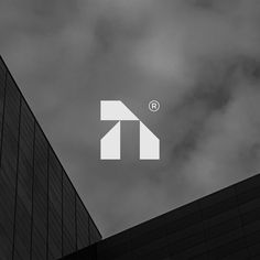 a tall building with the letter t on it's side against a cloudy sky