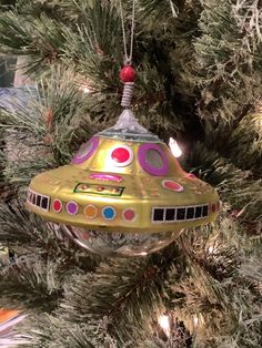 a christmas ornament hanging from a tree in the shape of a space ship