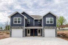 a large house with two garages in the middle of a lot that is under construction