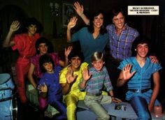 a group of young men and women posing for a photo with their hands in the air