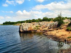 the water is calm and blue with rocks on both sides as well as trees in the distance