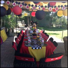 a mickey mouse birthday party with red and yellow table cloths, black and white polka dot napkins, and paper lanterns