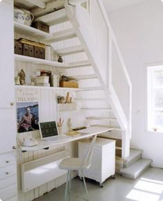 the stairs are white and there is a desk in front of it with a laptop on it