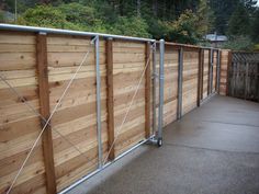 a wooden fence with metal bars on the top and bottom sections, along with concrete flooring