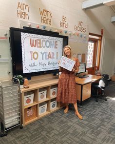 a woman standing in front of a tv holding up a sign that says welcome to year