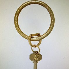 a gold colored keychain hanging from a metal ring on a white wall background