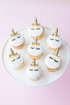 cupcakes decorated with white frosting and gold unicorn's noses on a plate