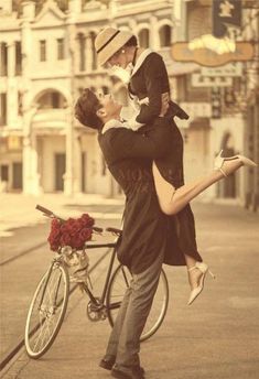 a man holding a woman on his back while standing next to a bike