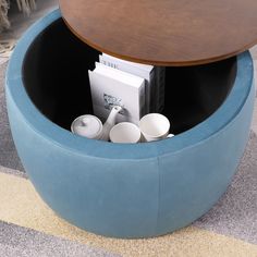 a blue round table with magazines and cups in the center on carpeted flooring