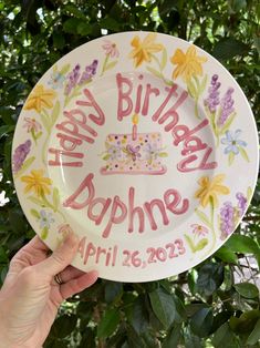 a hand holding up a plate with a birthday cake on it that says happy birthday doppme