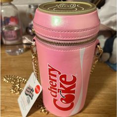 a pink canister with the word cake on it sitting on a table next to a gold chain