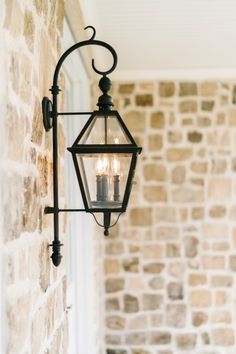 two lit candles are hanging from an iron lantern