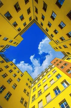 looking up at tall buildings from the ground with blue sky and clouds in the background