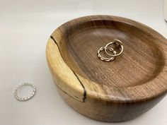 a wooden bowl with two wedding rings on it