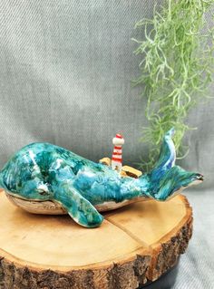 a blue ceramic dolphin with a red and white lighthouse sitting on it's back