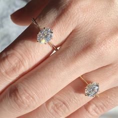 a woman's hand with two engagement rings on her left and the middle finger