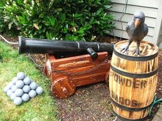 a bird sitting on top of a wooden barrel next to a cannon and some balls