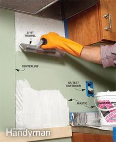 a man is painting the walls in his kitchen with yellow gloves and paint rollers