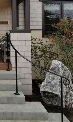 there is a large rock sitting on the steps in front of this house with black iron railings