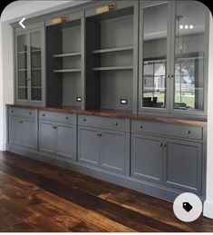 an empty room with gray cabinets and wood floors