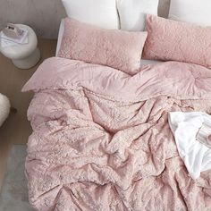 an unmade bed with pink sheets and pillows on the floor next to a white chair