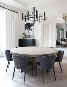 a dining room table with chairs and a chandelier hanging from the ceiling above it