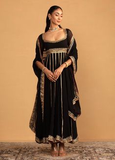 Elevate your ethnic wardrobe with the stunning Black Georgette Embroidered Anarkali set, crafted from luxurious georgette. The black Anarkali is exquisitely adorned with intricate gota work and boasts a flowy silhouette that adds grace to your movements. Paired with a classic churidar for a streamlined look. The ensemble is completed with a lightweight georgette dupatta, enhancing its traditional charm. Ideal for Cocktail parties, Sangeet nights or celebratory events, this ensemble combines time Anarkali Designs, Black Anarkali, Georgette Anarkali, Embroidered Anarkali, Georgette Dupatta, Gota Work, Indian Wedding Wear, Wedding Wear, Anarkali