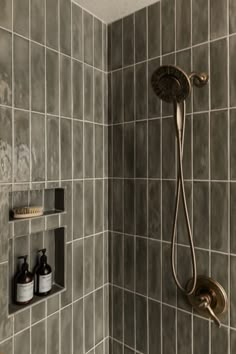 a shower head and hand held shower faucet in a tiled bathroom with gray walls