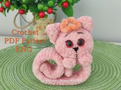 a pink teddy bear sitting on top of a green rug next to a potted plant