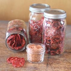 three jars filled with different types of food on top of a wooden table next to each other