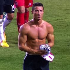 a shirtless man holding a soccer ball in his hands while standing on the field