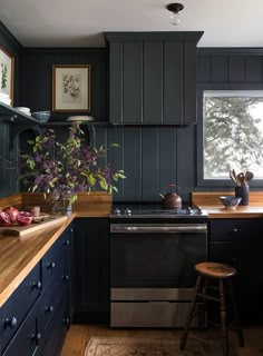 a kitchen with dark blue cabinets and wooden counter tops is pictured in this image, there are two stools next to the stove