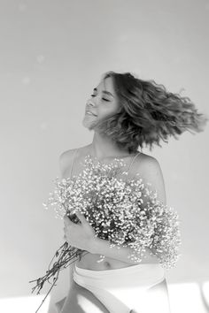 a woman holding a bunch of flowers in her hand and looking up at the sky