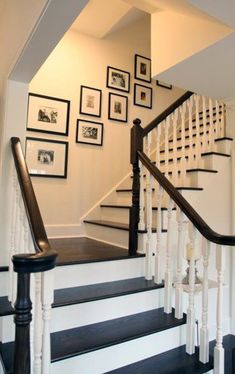 a staircase with framed pictures on the wall and wooden handrails, along with black and white stairs