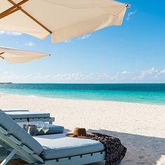 two lounge chairs and an umbrella on the beach