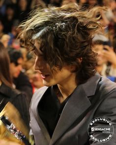 a man with long hair standing in front of a crowd