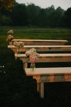 several wooden benches lined up with flowers in vases on top of each bench,