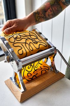 a person with tattoos on their arm is using a machine to make something yellow and black