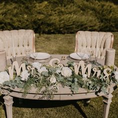 the table is set with white flowers and greenery