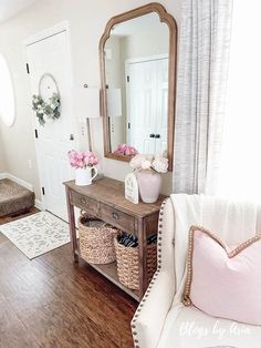 a living room filled with furniture and flowers on top of a wooden table in front of a mirror