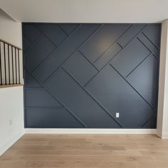 an empty room with wood flooring and blue painted wall in the background is a stair case