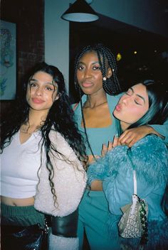 three women standing next to each other posing for the camera