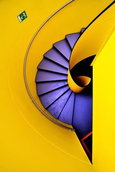 an image of a spiral staircase going up the side of a yellow building with blue stairs