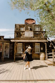 a woman standing in front of a wooden building