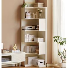 a white shelf with books and other items on it in a room next to a window