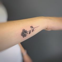 a woman's arm with a small rose tattoo on the left side of her arm