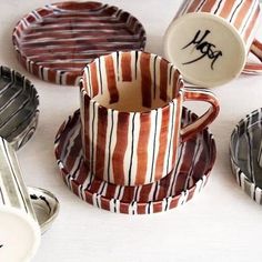 coffee cups and saucers with graffiti written on them sitting on a white table top