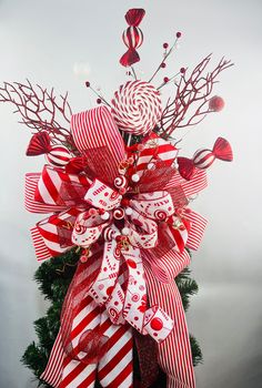 a red and white christmas tree with candy canes on it's bow,