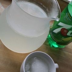 a pitcher of water next to a cup with ice